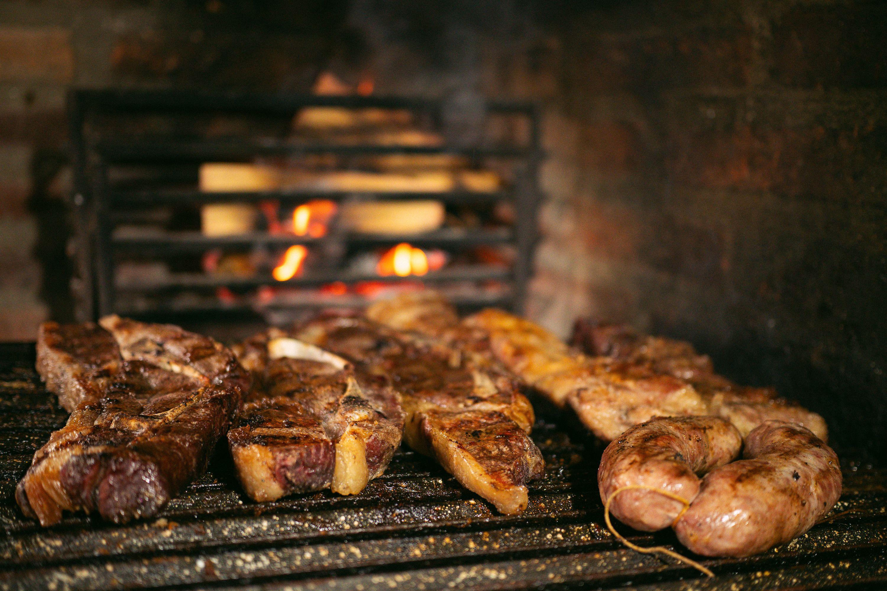 Close-up of grilled meat and sausages on an open fire barbecue, showcasing a rustic cooking style.